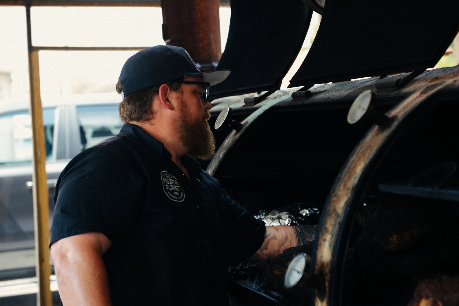 The Fourth Planet BBQ pitmaster tending the offset smoker